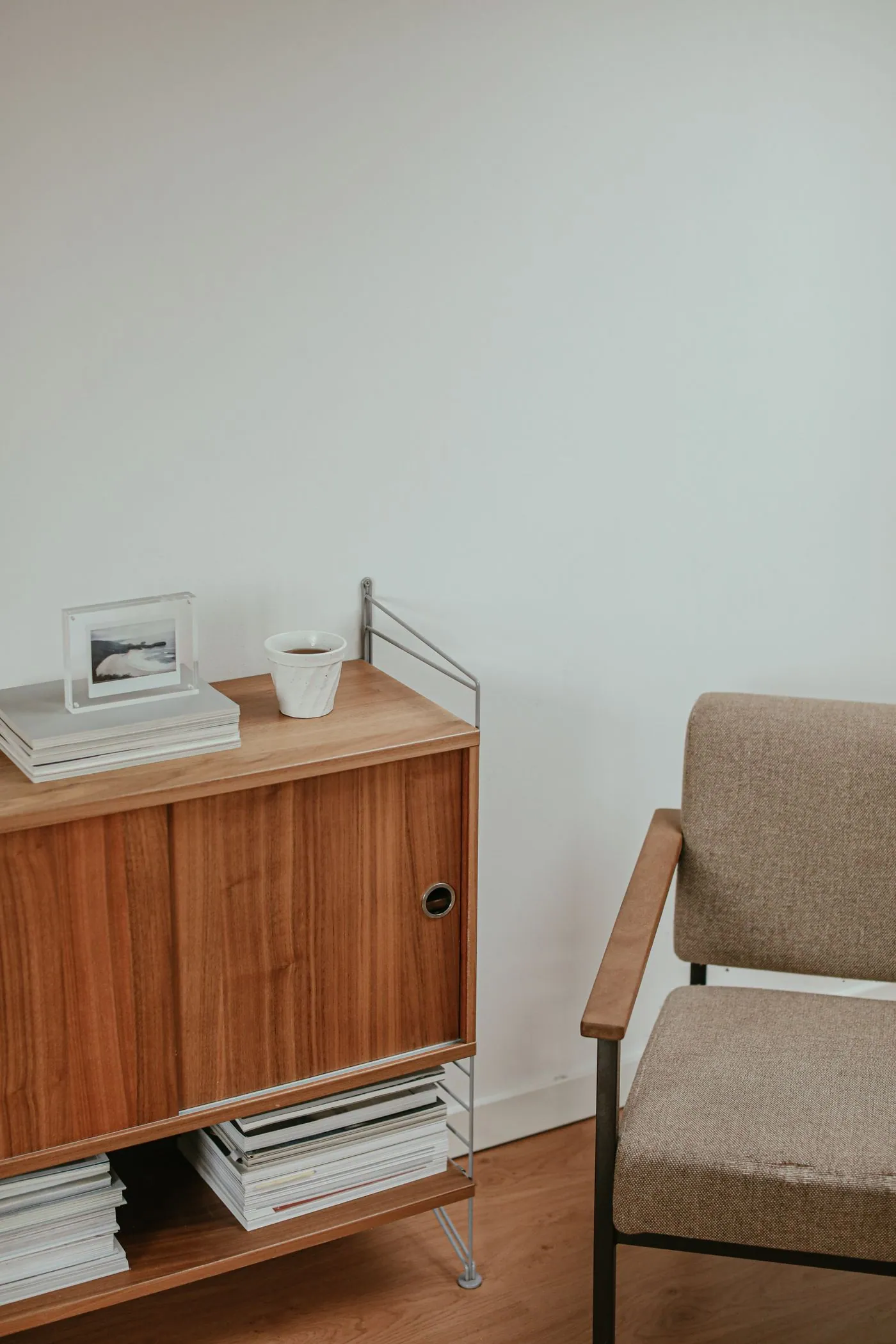Wooden cabinet with sliding doors beside an upholstered armchair
