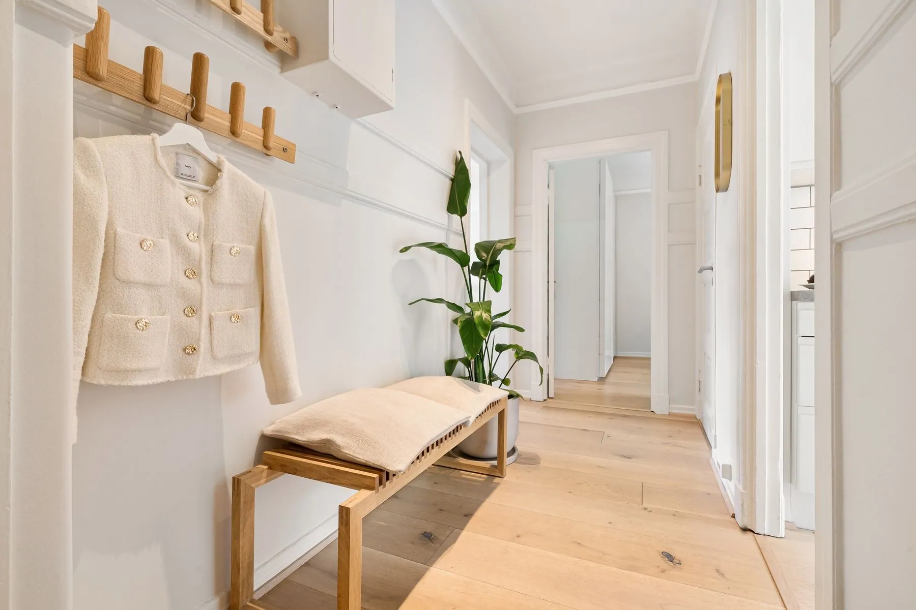 Light hallway with an oak bench, wall hooks and a wooden floor