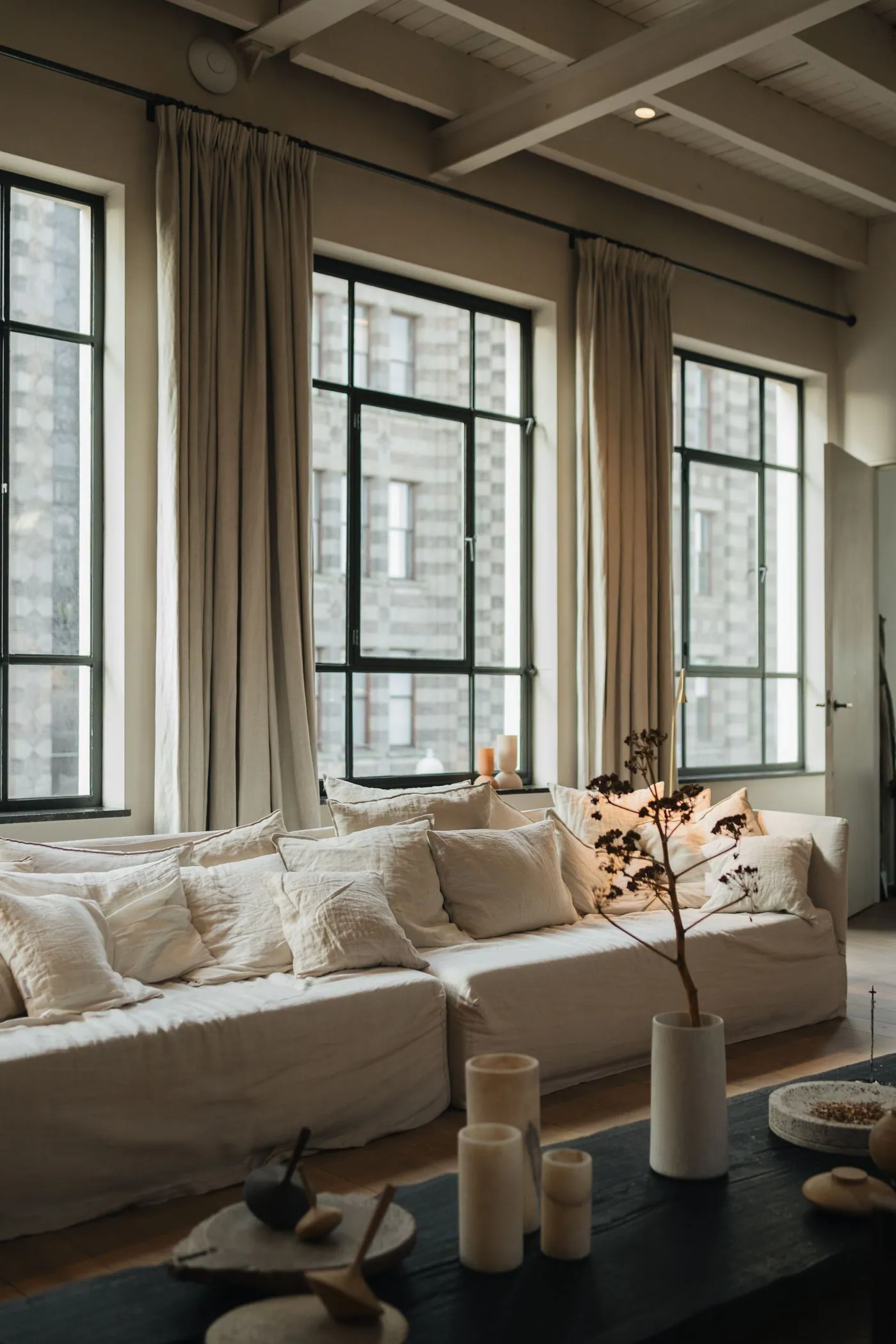 Linen sofas with soft cushions in front of tall black-framed windows